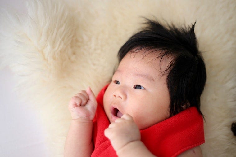 bébé aux cheveux noirs sur une couverture douce - qu'est-ce que l'agressivité mignonne