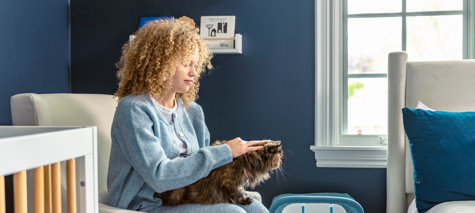 pregnant woman sitting in nursery with cat on lap