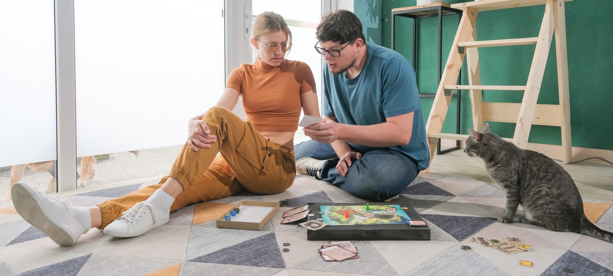 two people playing board game with cat watching