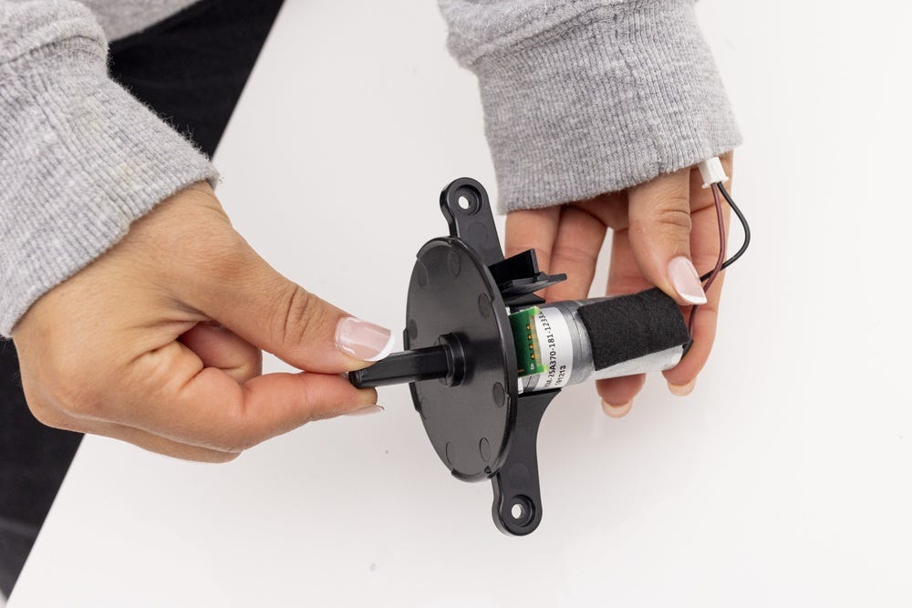 Sliding the black, circular dispenser adapter onto the new motor assembly