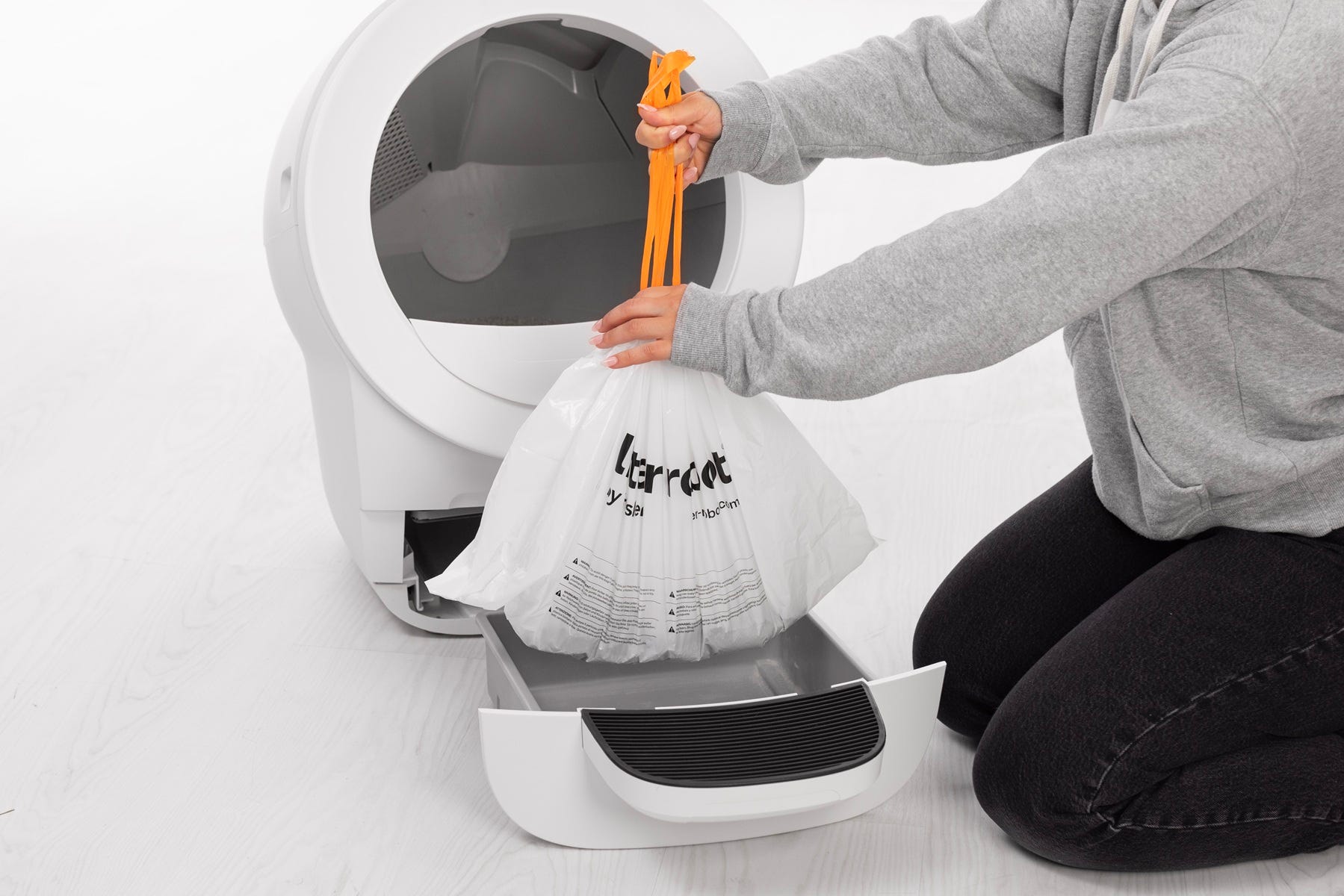 Pulling waste drawer liner string to close bag