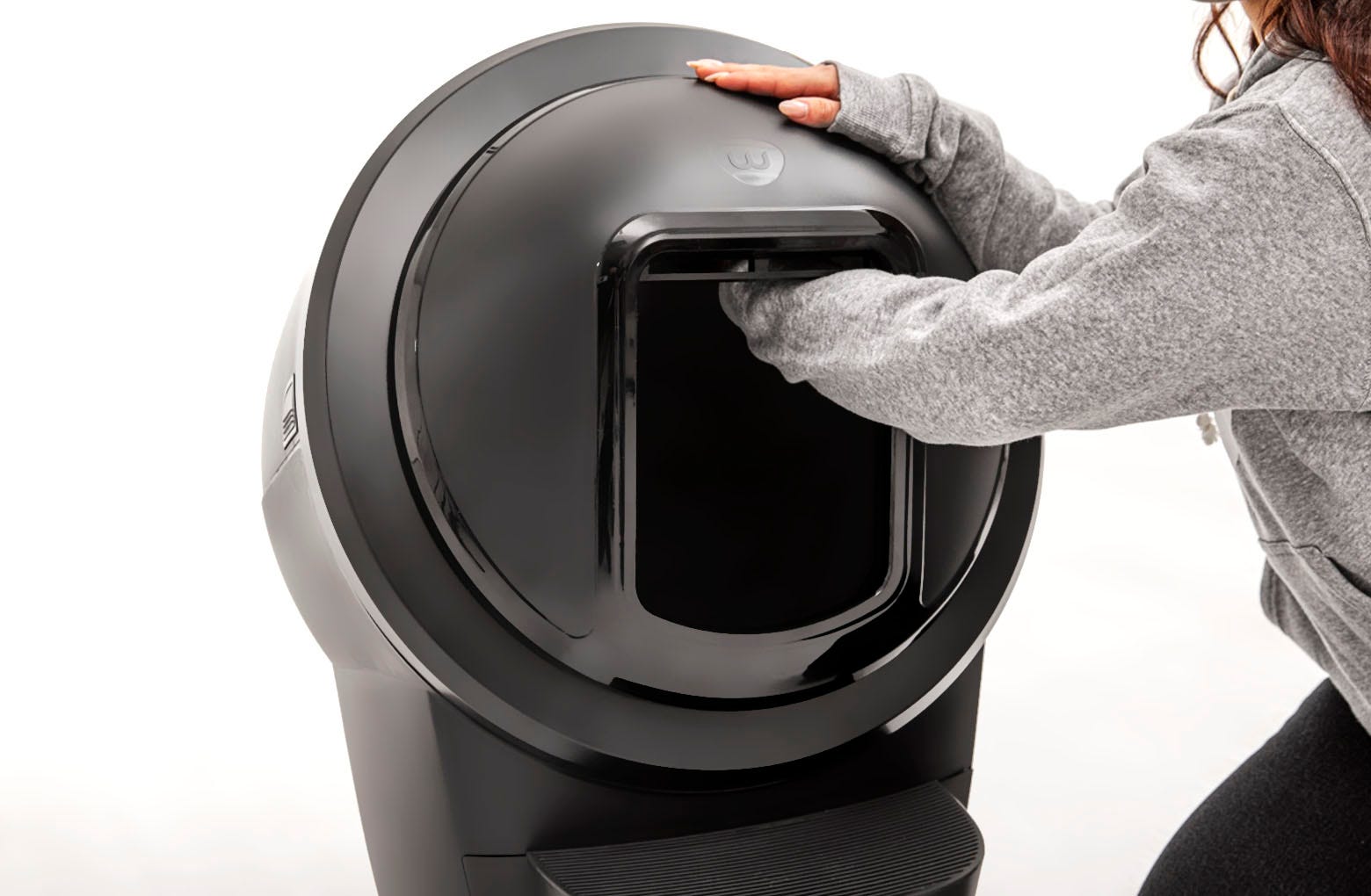 Reaching inside the Litter-Robot shield opening and detaching the hook on the inside