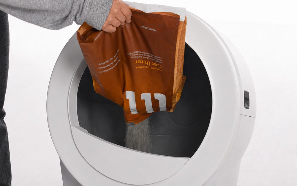 Litter being poured into the globe opening from a bag
